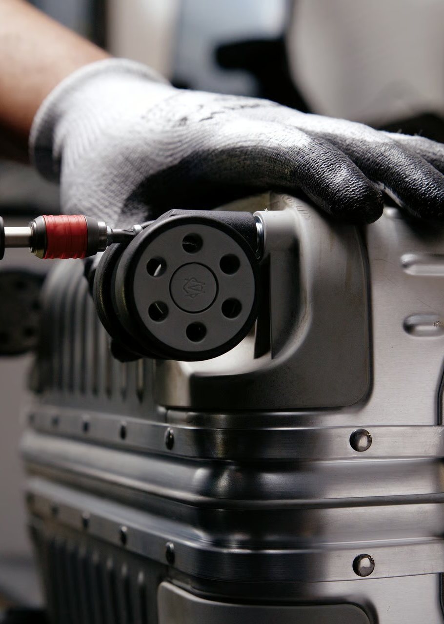 Mains gantées qui remontent une roue sur une valise en aluminium